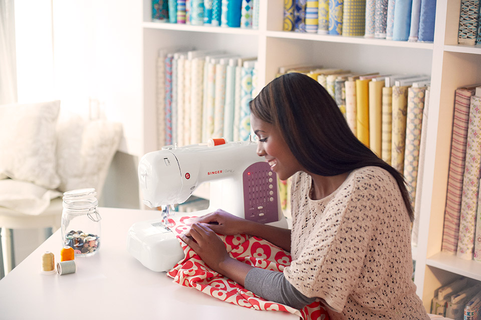 Girl seated at Singer sewing machine